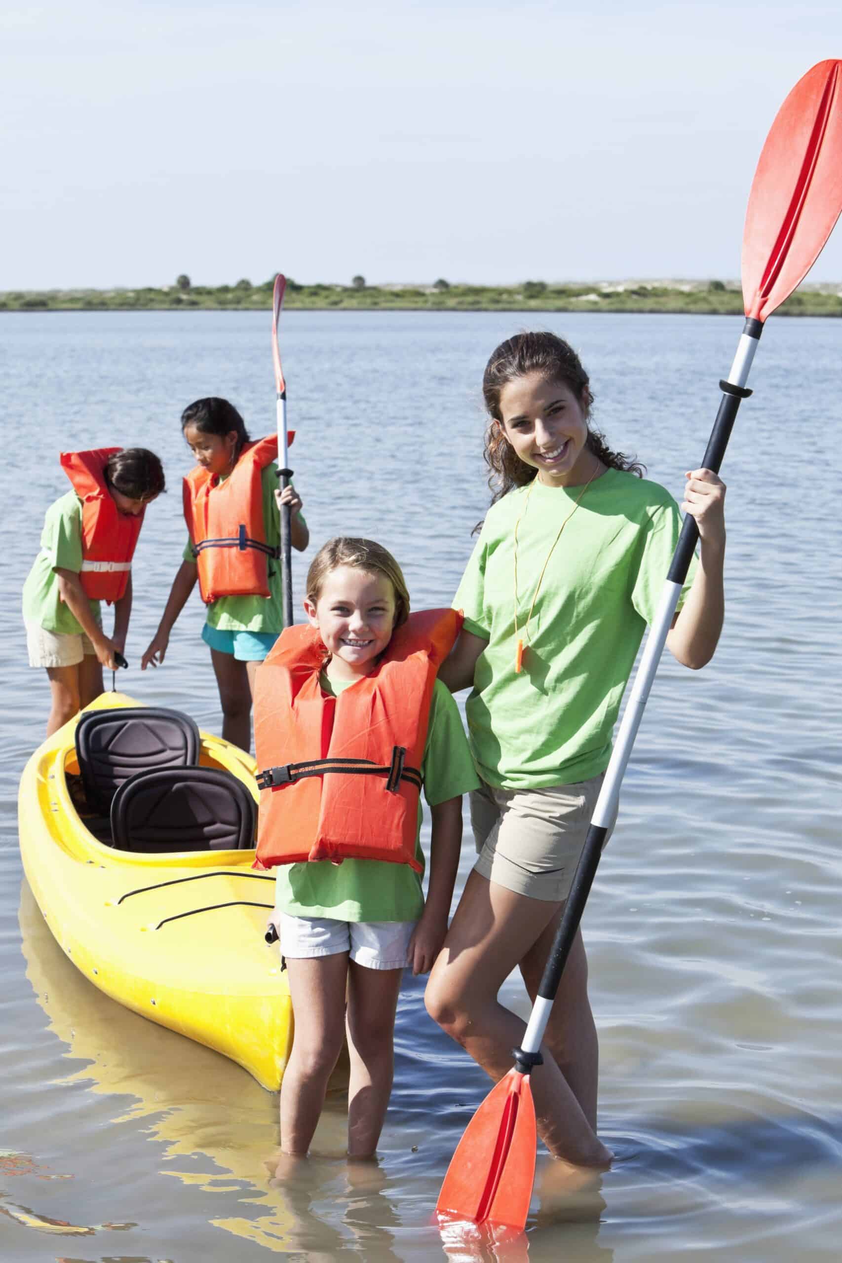 Two girls in front of a kayak.